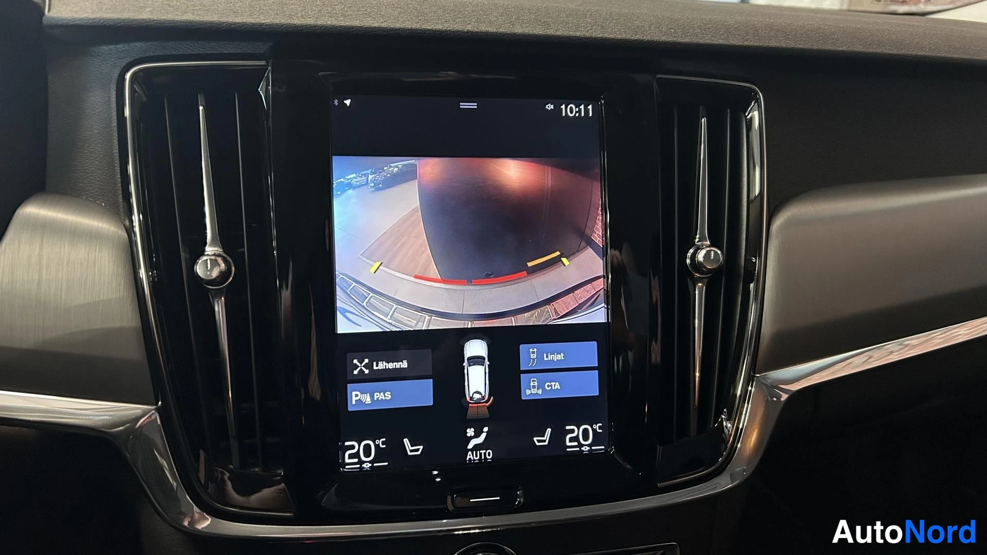 Muu: Infotainment-näyttö, jossa näkyy peruutuskameran kuva ja parkkitilanteen ikonit.