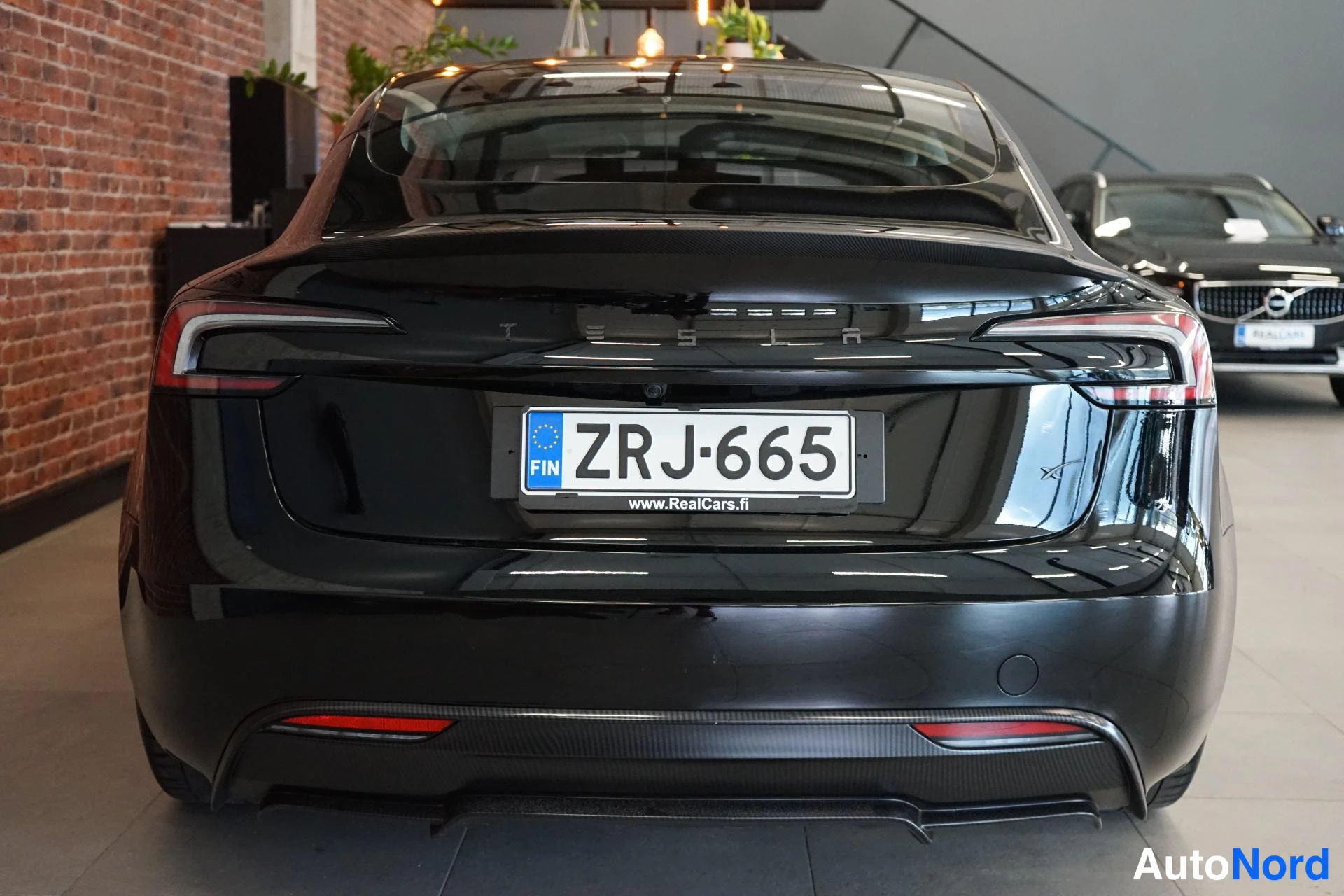 Takaa: Tesla Model 3:n takaosa, TESLA-teksti ja rekisterikilpi.