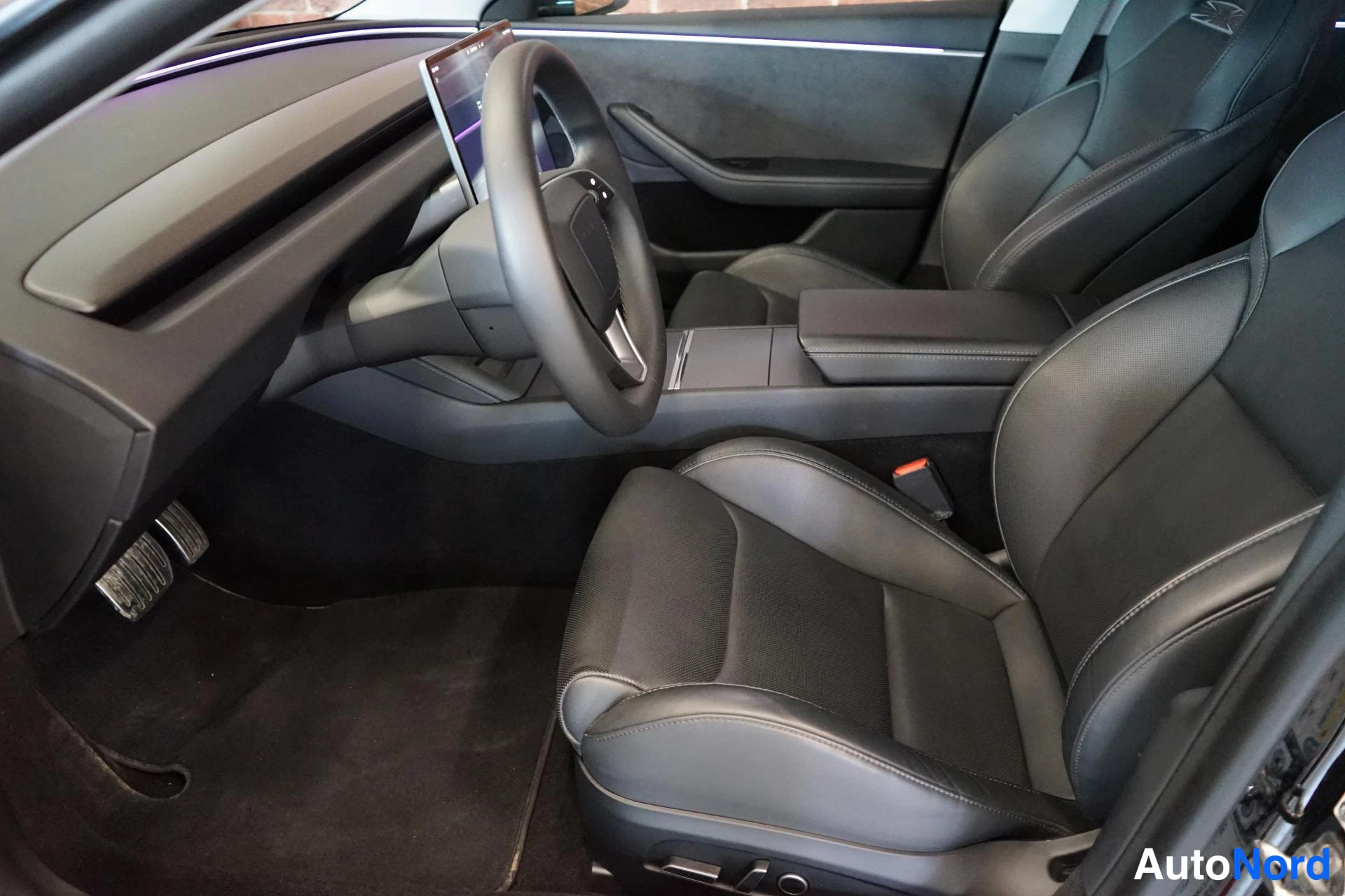 Muu: Tesla Model 3:n etusohjaamo ja kaksi etuistuinta tummalla nahkaverhoilulla.