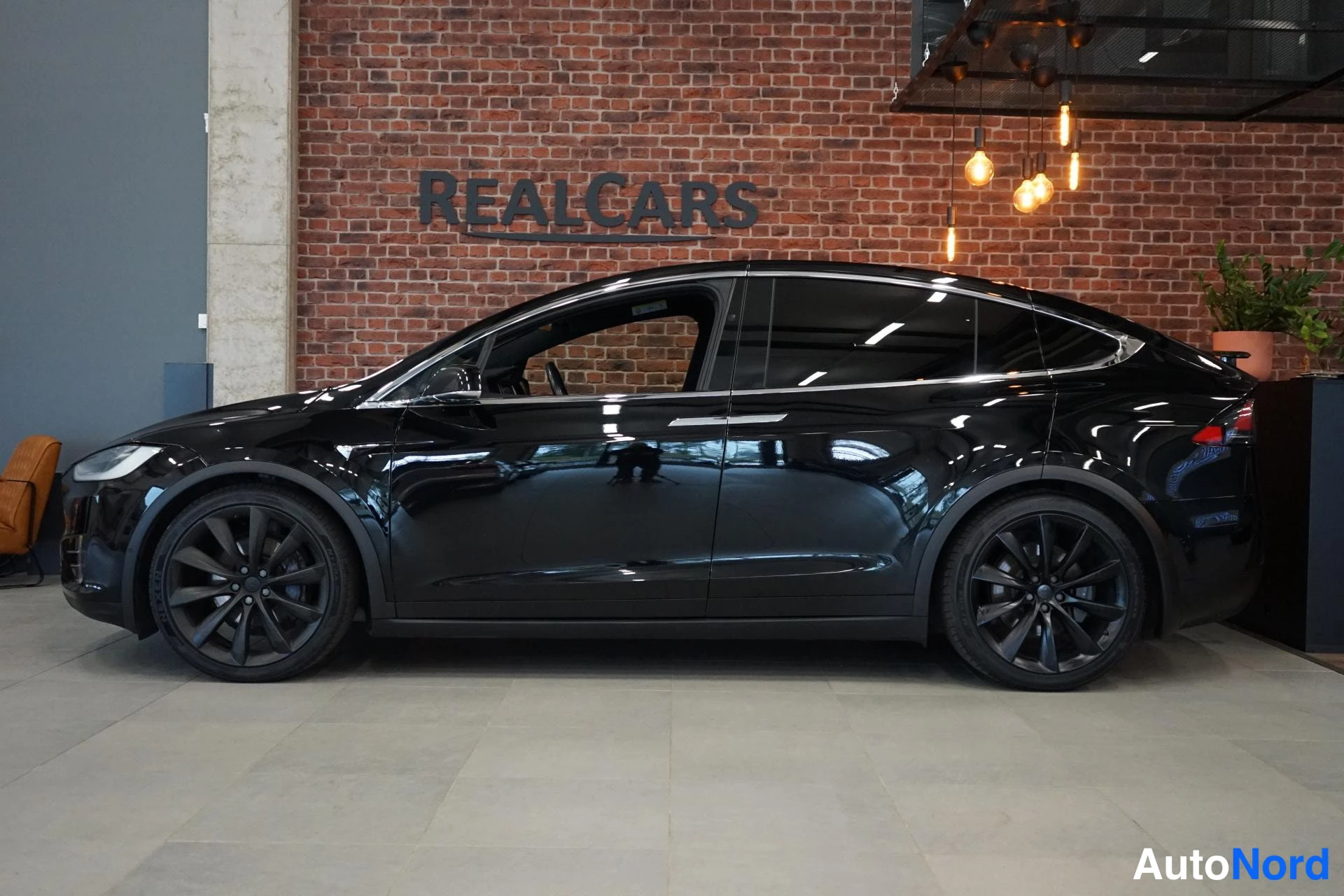 Etuviisto, nokka vasemmalle: Mustan Tesla Model X:n sivuprofiili oikealta puoleltä
