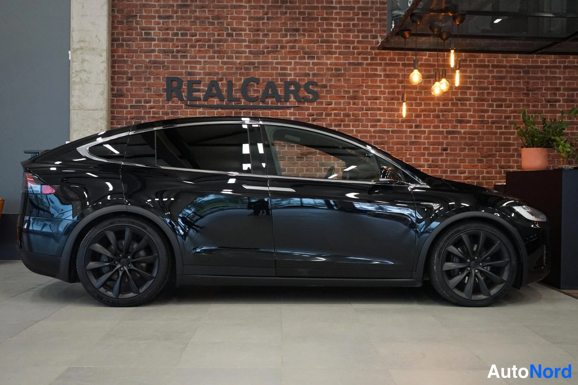 Takaviisto: Mustan Tesla Model X:n sivuprofiili vasemmalta puoleltä