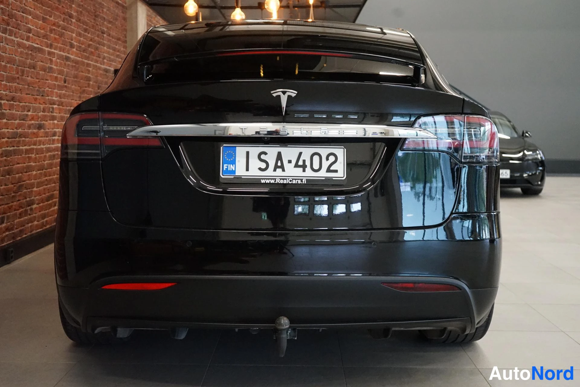 Takaa: Musta Tesla Model X takaa: takavalot, T-logot ja rekisterikilpi, vetokoukku takapuskurissa.