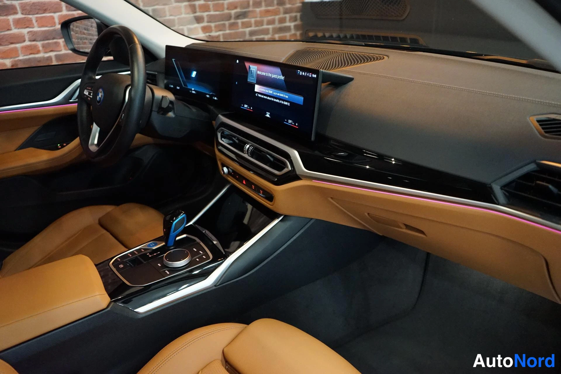 Muu: Auton sisätilat: tumma kojelauta, pancreatied näytöt, ruskeat nahkaistuimet ja BMW-ohjauspyörä.