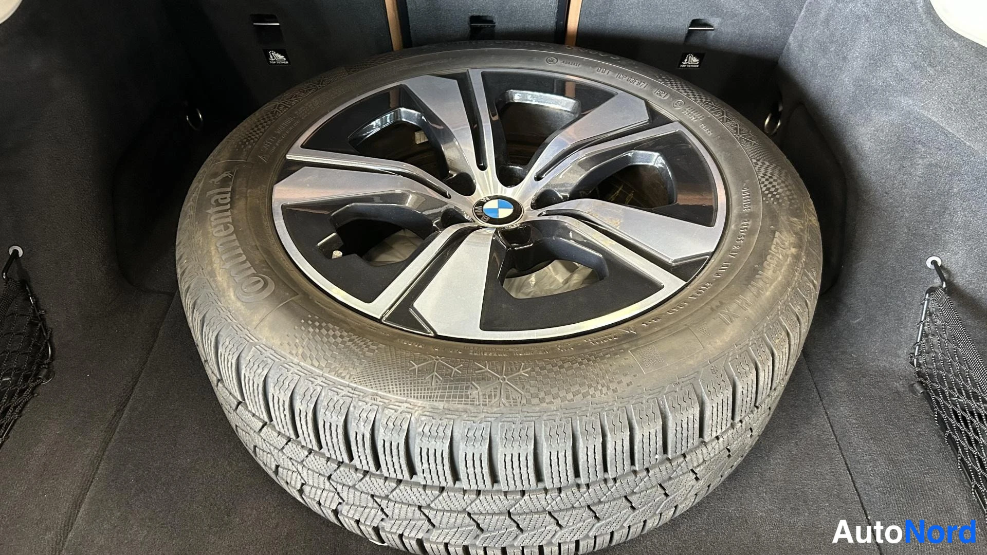 Yksityiskohta: Tavaratilassa säilytetty varapyörä talvirenkaalla; BMW-merkillinen vanteellinen Continental-talvirengas kuvattu ylhäältä
