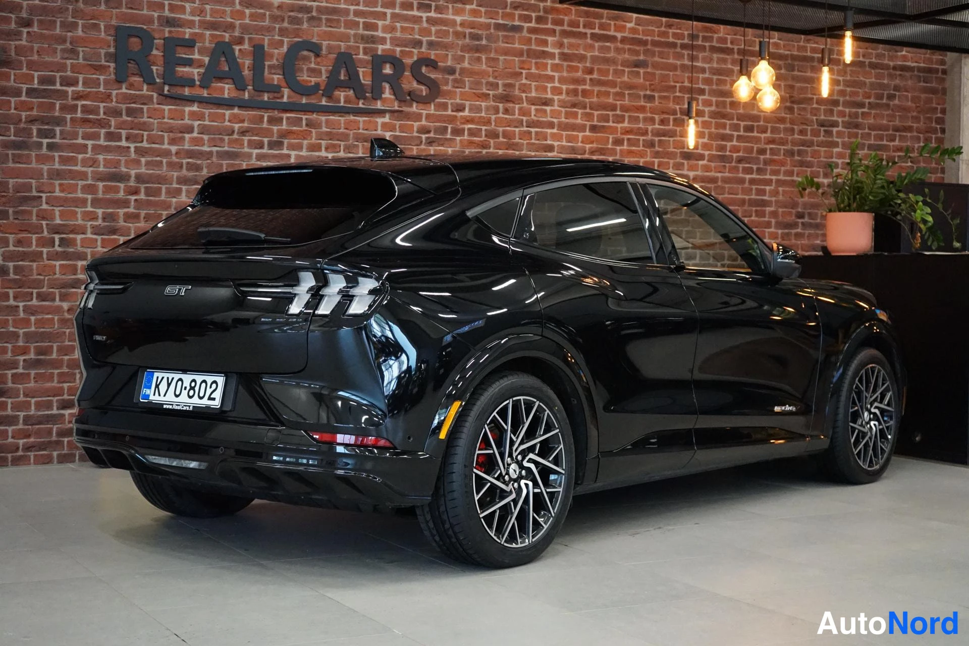 Takaviisto: Mustan Ford Mustang Mach-E:n takaosa ja oikea kylki kuvattuna sisätiloissa.