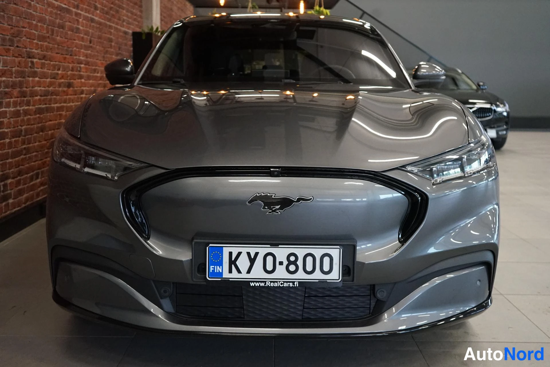 Edestä: Auton etupää edestäpäin; harmaassa etugrilliä reunustaa Mustang-merkki ja Eurooppa-laatta KY0-800.
