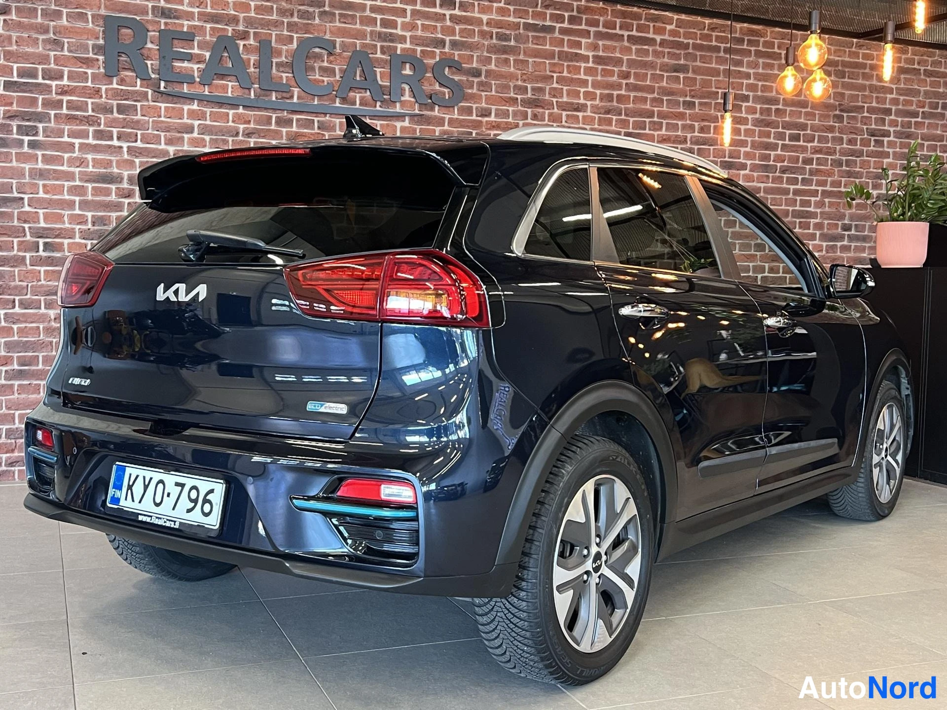 Takaviisto: Mustan Kia Niro Electric -auton takaosa ja oikea sivu viistosti showroomissa.
