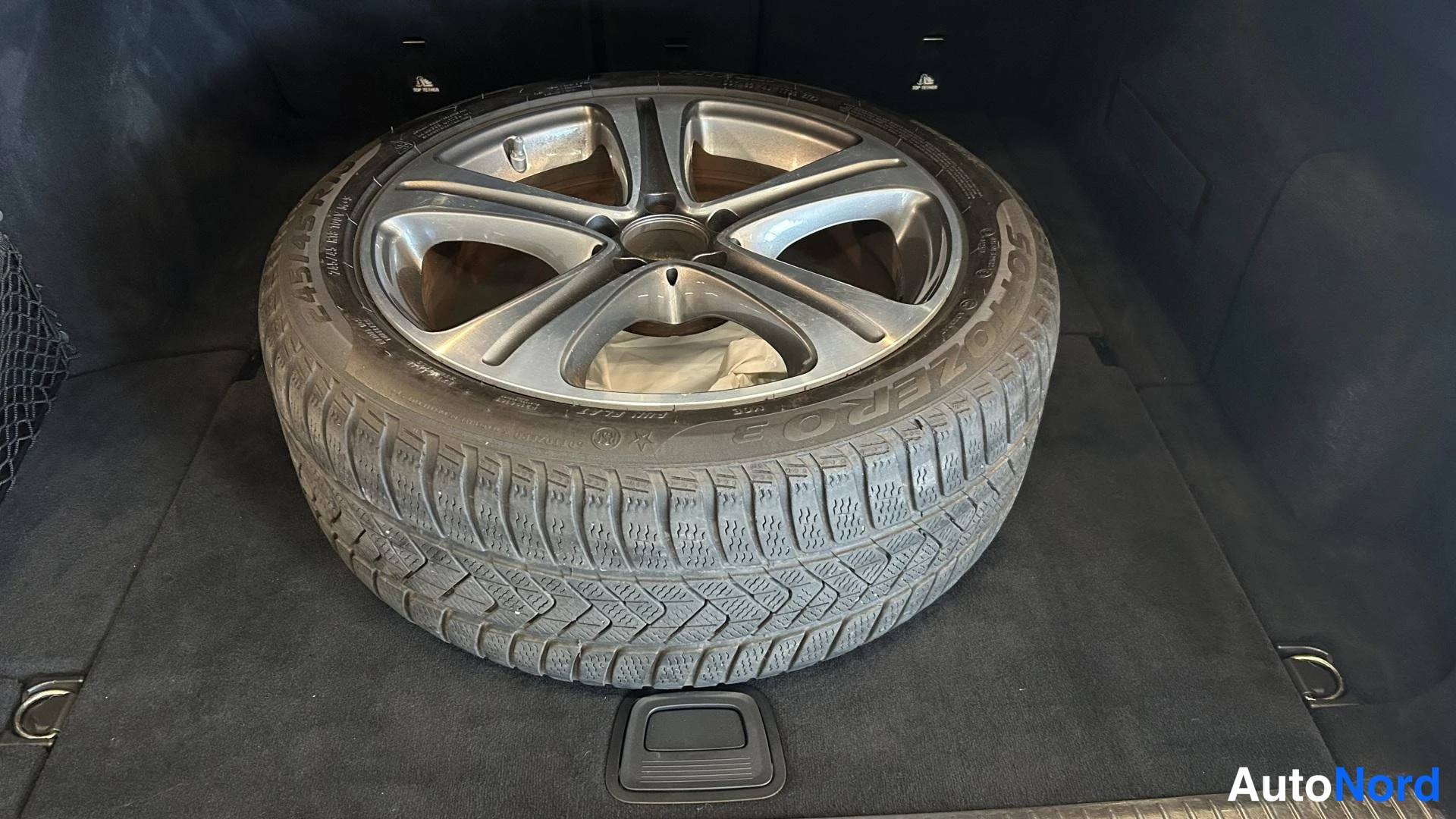 Muu: Varapyörä Pirelli-renkaalla ja hopeisella pinnanpyörällä tummassa tavaratilassa.