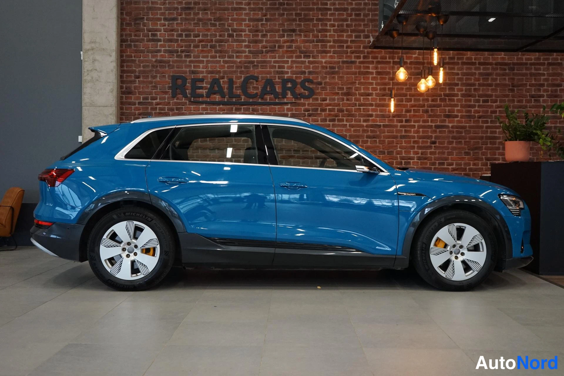 Takaviisto: Audi e-tron takaviisto oikealta, sininen kori, hopeat vanteet.