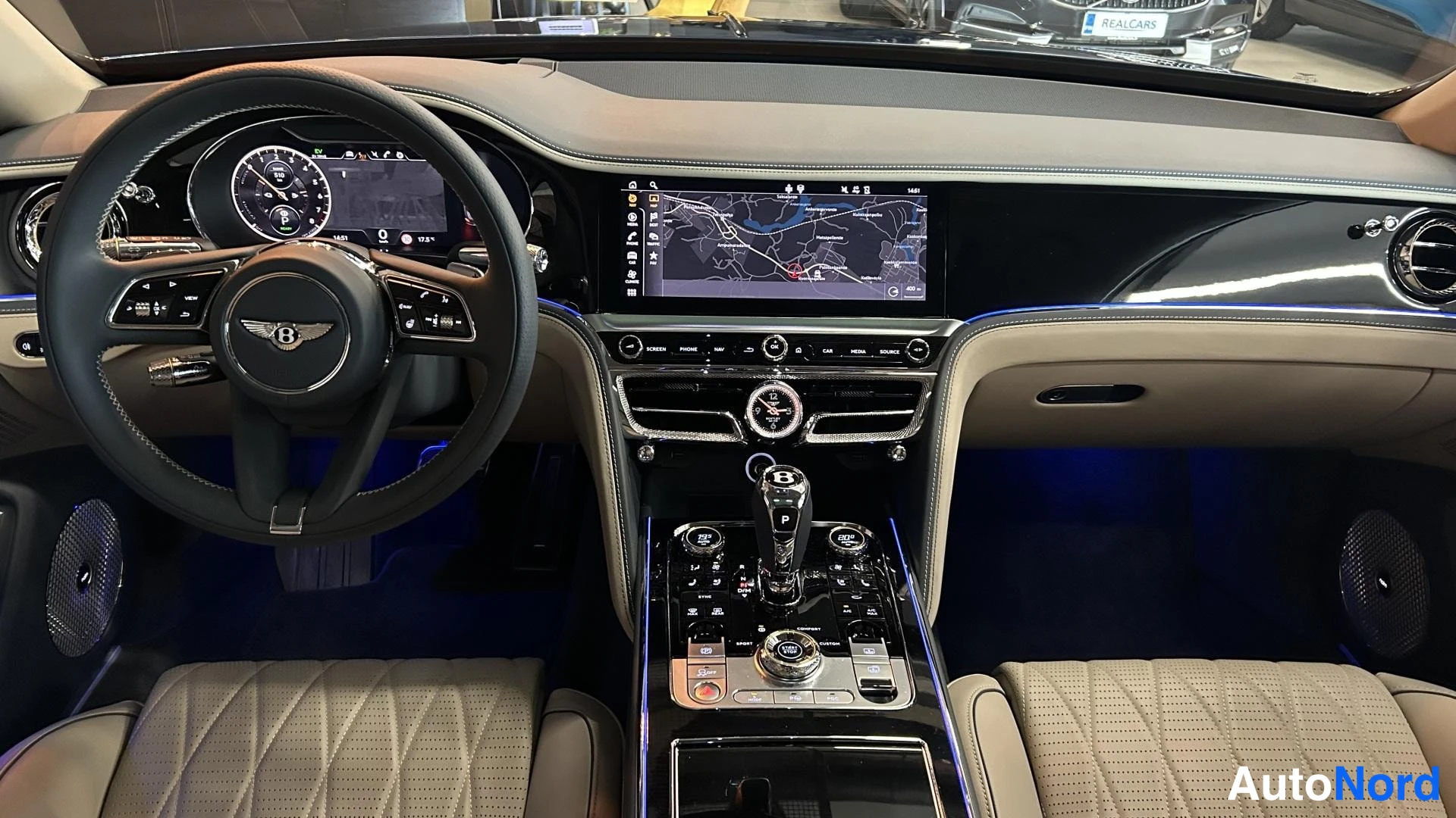 Edestä: Bentley-ohjauspyörä, digitaalinen mittaristo, keskikonsolin karttanäyttö ja rotary-valitsimet.