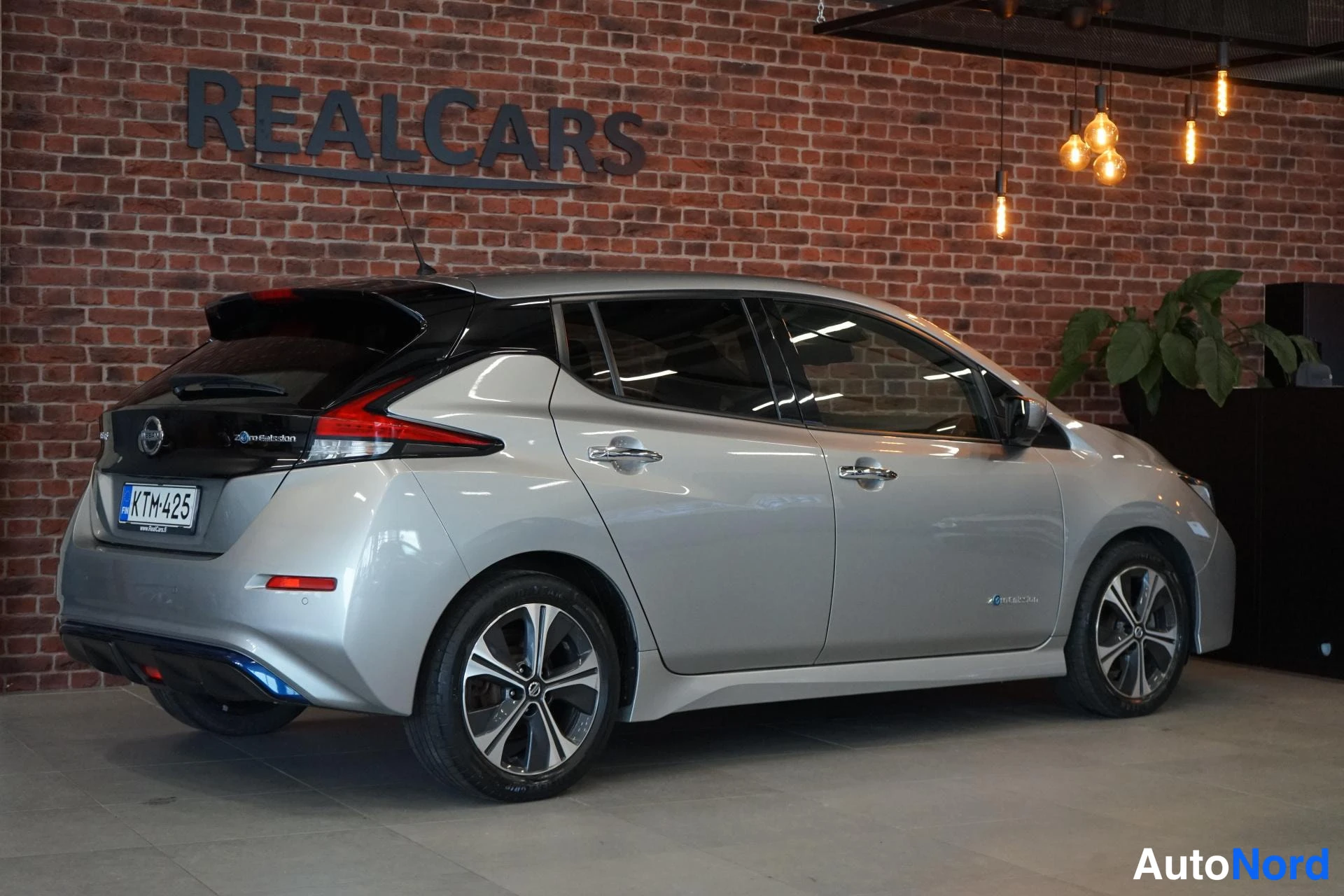 Takaviisto: Nissan Leaf -henkilöauto takaa- ja sivulta kuvattuna, hopeisenä, rekisterikilpi.