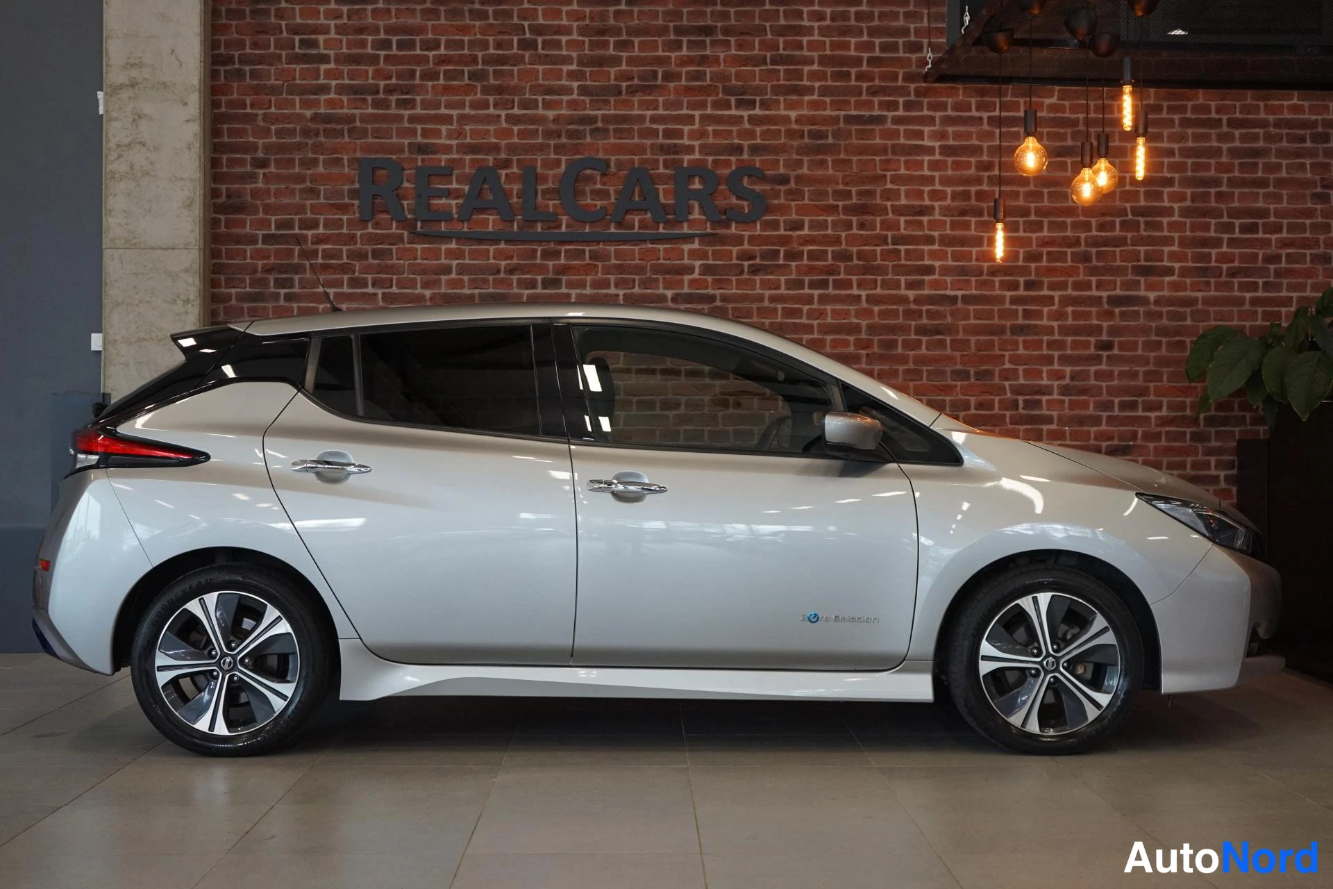 Takaviisto: Nissan Leaf -henkilöauto sivusta takanurkkaan kuvattuna, hopeinen koripinta ja musta lasikatos.