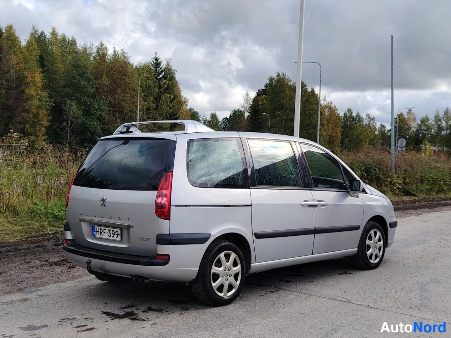 Takaviisto: Hopeanvärinen tila-auto takakulmasta oikealta, takavalot, rekisterikilpi ja oikea kylki näkyvissä.