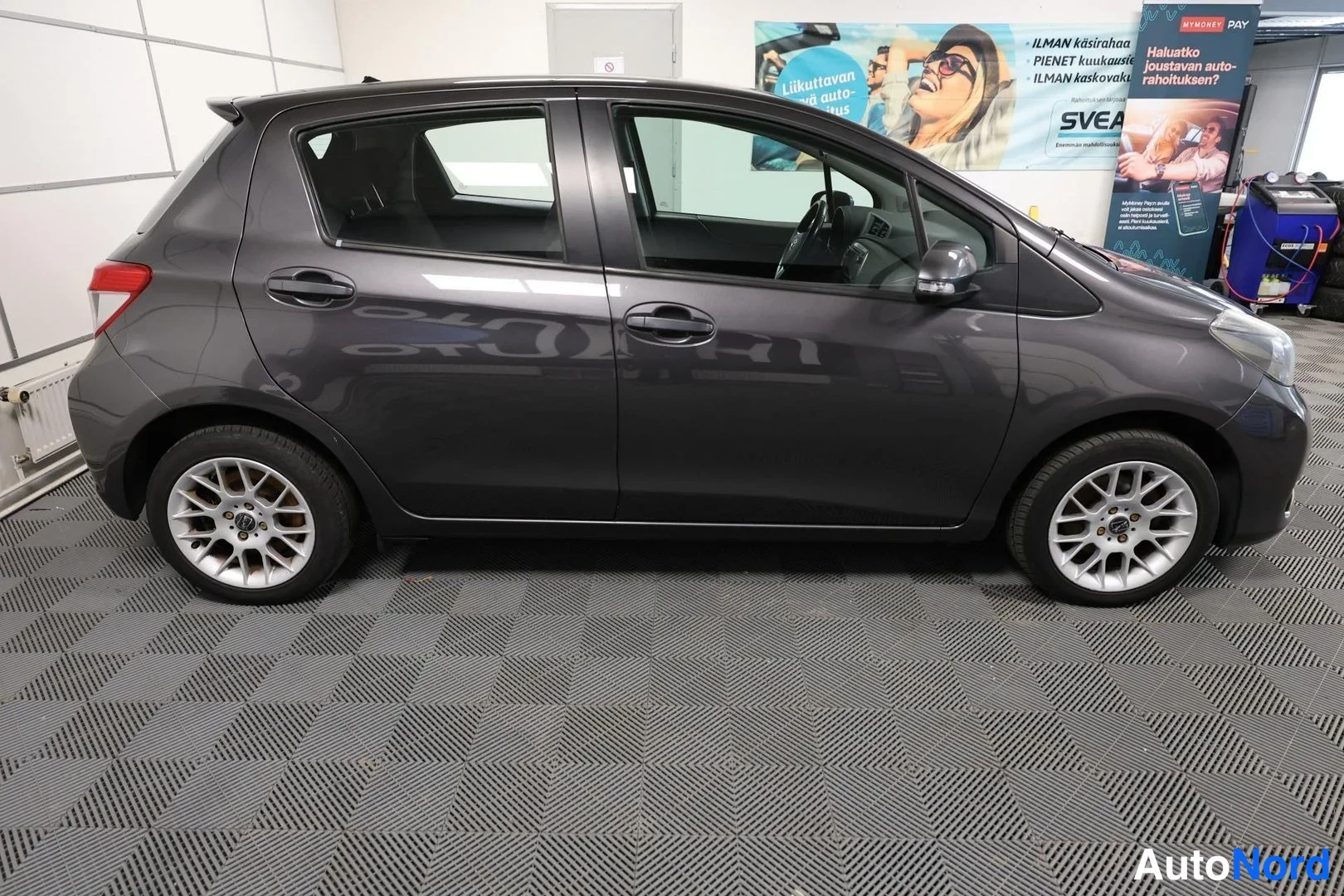 Sivulta: Toyota Yaris -henkilöauto sivulta, tummanharmaa.