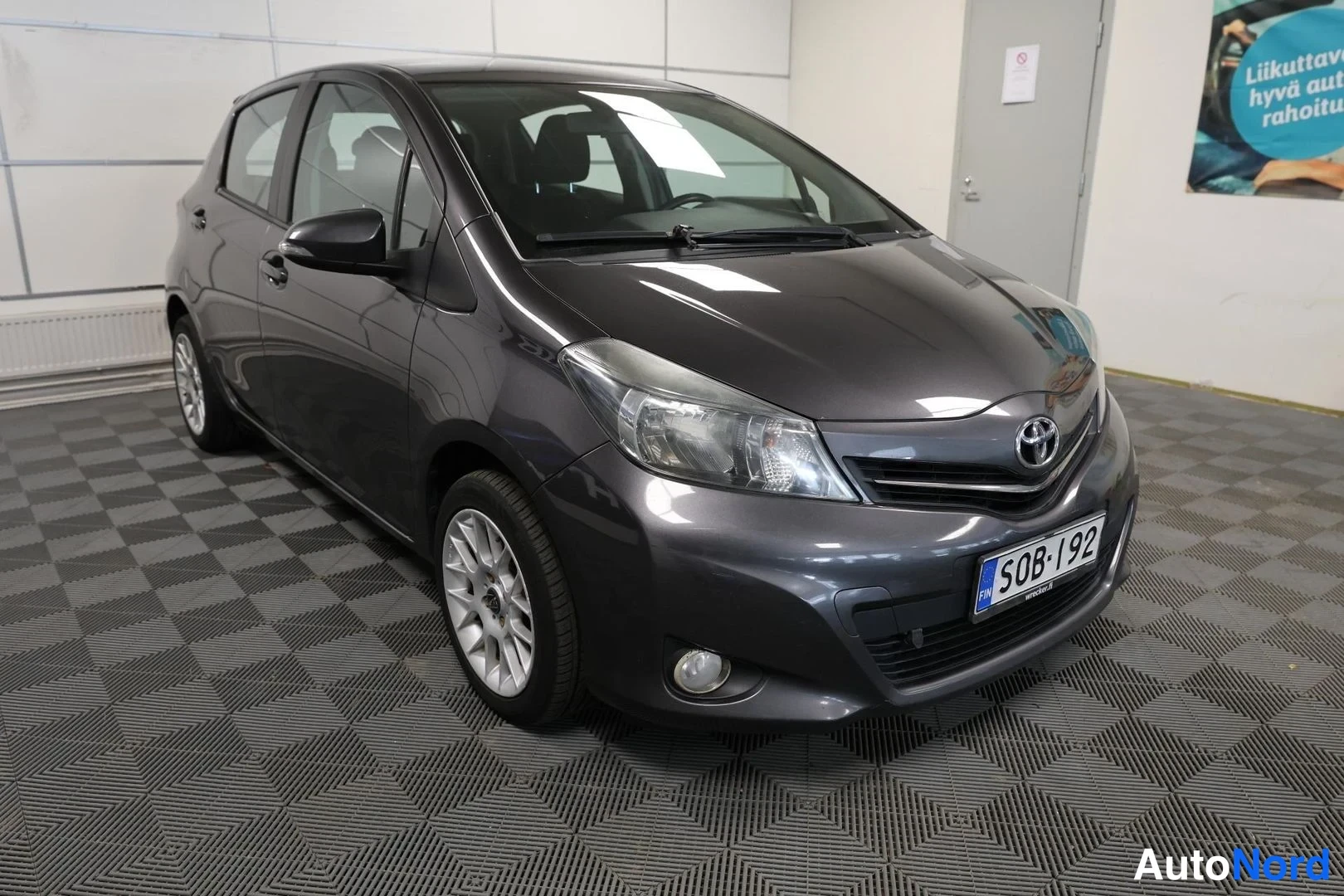 Etuviisto, nokka oikealle: Toyota Yaris -henkilöauto etuviistöltä oikealta, tummanharmaa.