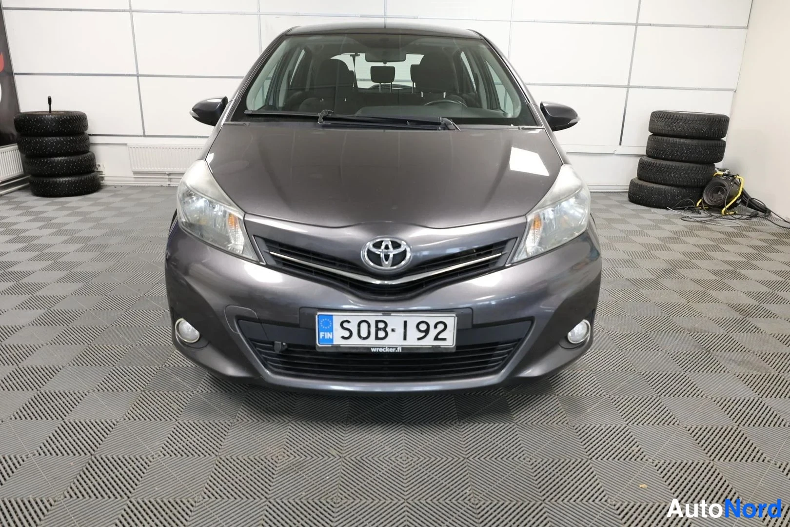 Edestä: Toyota Yaris -henkilöauto edestä, tummanharmaa.