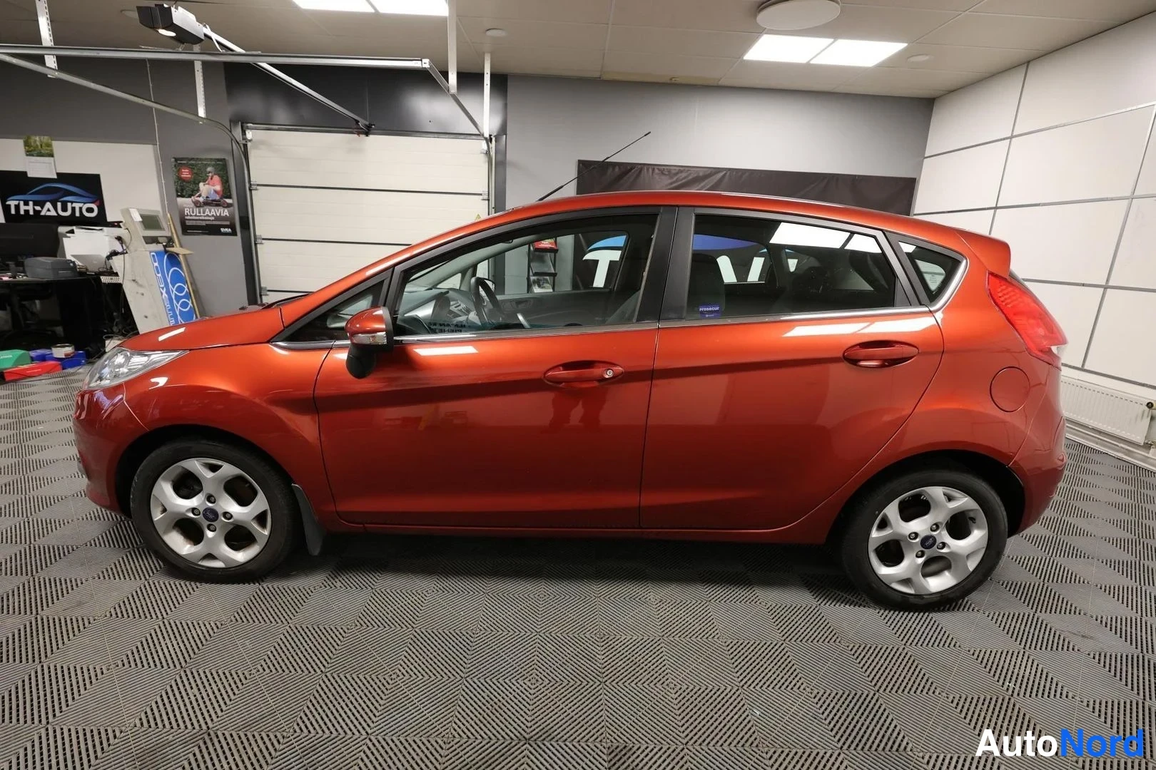 Sivulta: Punaisenruskea viistoperäinen Ford Fiesta sivulta vasemmalta kuvattuna autotallissa.
