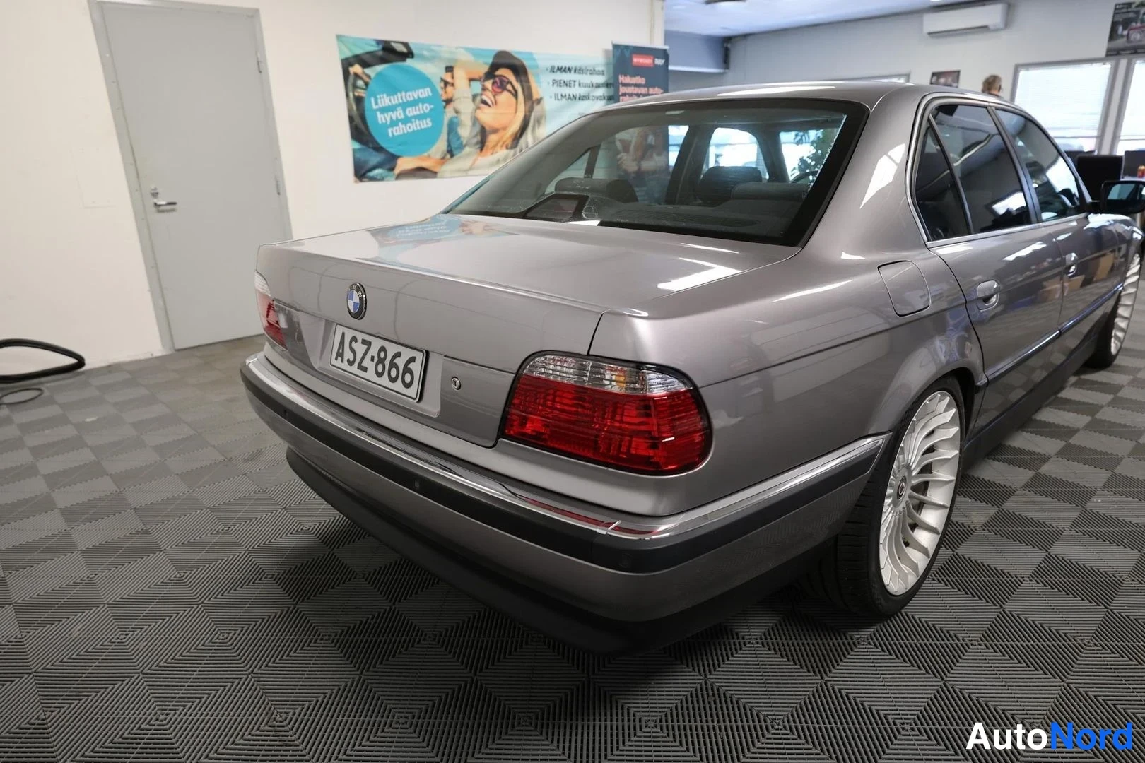 Takaviisto: BMW-sedan takaosa ja vasen kylki kulmasta autotallissa, rekisteri
