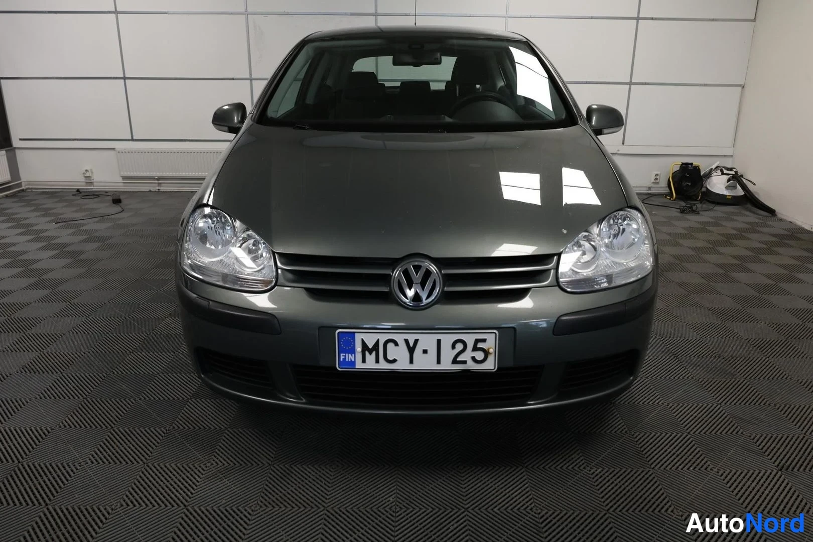 Edestä: Auton etunäkymä suoraan edestä, VW-merkki ja rekisteritunnus näkyvät.
