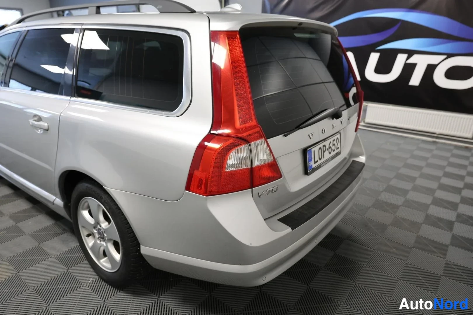 Takaviisto: Farmariauton takanurkka ja peräosa lähikuvassa, rekisteri, takana TH-Auto-mainosseinä.