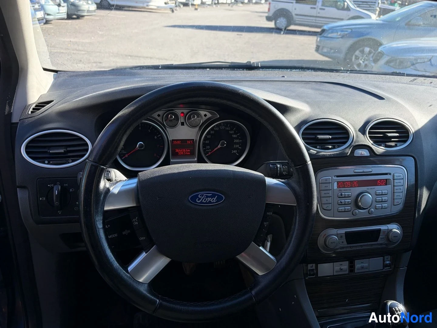 Edestä: Ford-merkkinen ohjauspyörä ja mittaristo, radioyksikkö näytöllään 30.09.26 15:02 vasemmassa ohjaamosta kuvattuna.