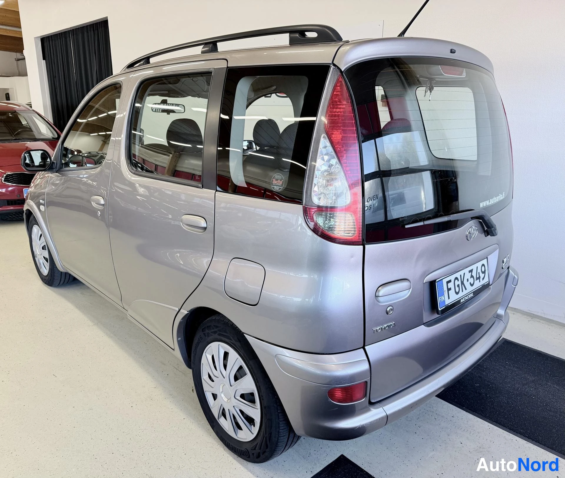 Takaviisto: Hopeanvärinen Toyota Yaris Verso kolmesta neljäsosan takanäkymässä, rekisteritunnus, takaistuimet osittain näkyvissä ikkunoiden läpi.