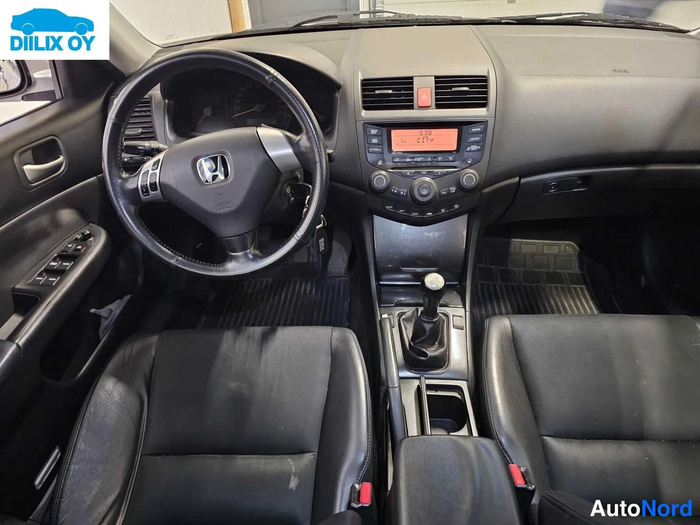 Etuistuimet: Cockpit view of a car interior with black leather front seats, a three-spoke steering wheel featuring the Honda logo, and a center console with an automatic gea