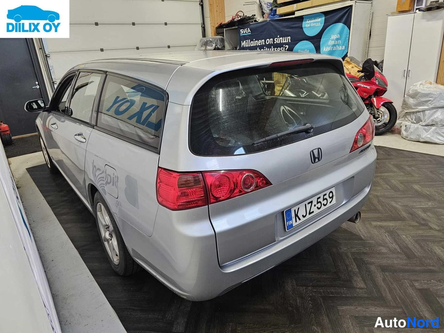 Takaa: Close-up rear view of the silver Honda station wagon in an indoor garage setting. The rear window, wiper, tail lights, boot lid badge and license plate are clea