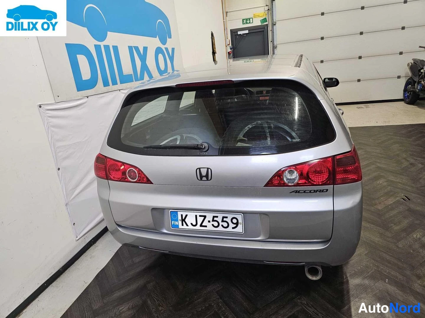Takaa: Hopea Honda Accord -farmarin takapää suoraan takaa kuvattuna, ACCORD-merkintä ja rekisterikilpi.