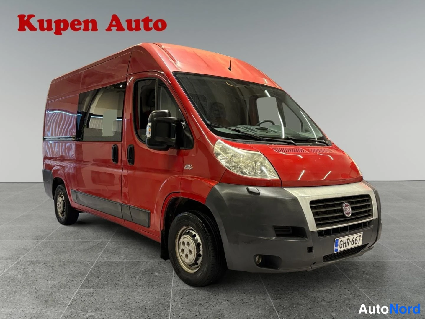 Etuviisto, nokka oikealle: Punaisen Fiat Ducato -pakettiauton etukulmanäyttö oikealta, keulalla Fiat-merkki ja rekisterikilpi.