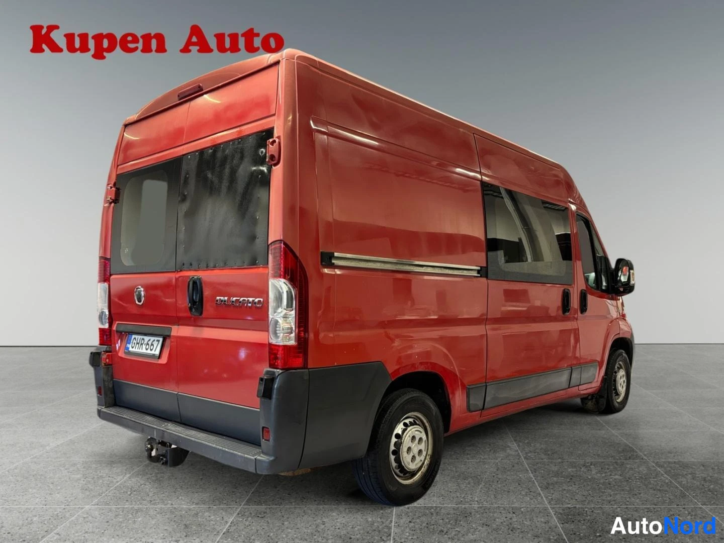 Takaviisto: Punaisen Fiat Ducato -pakettiauton takakulmanäyttö, peräluuku DUCATO-tekstillä ja rekisterikilpi.