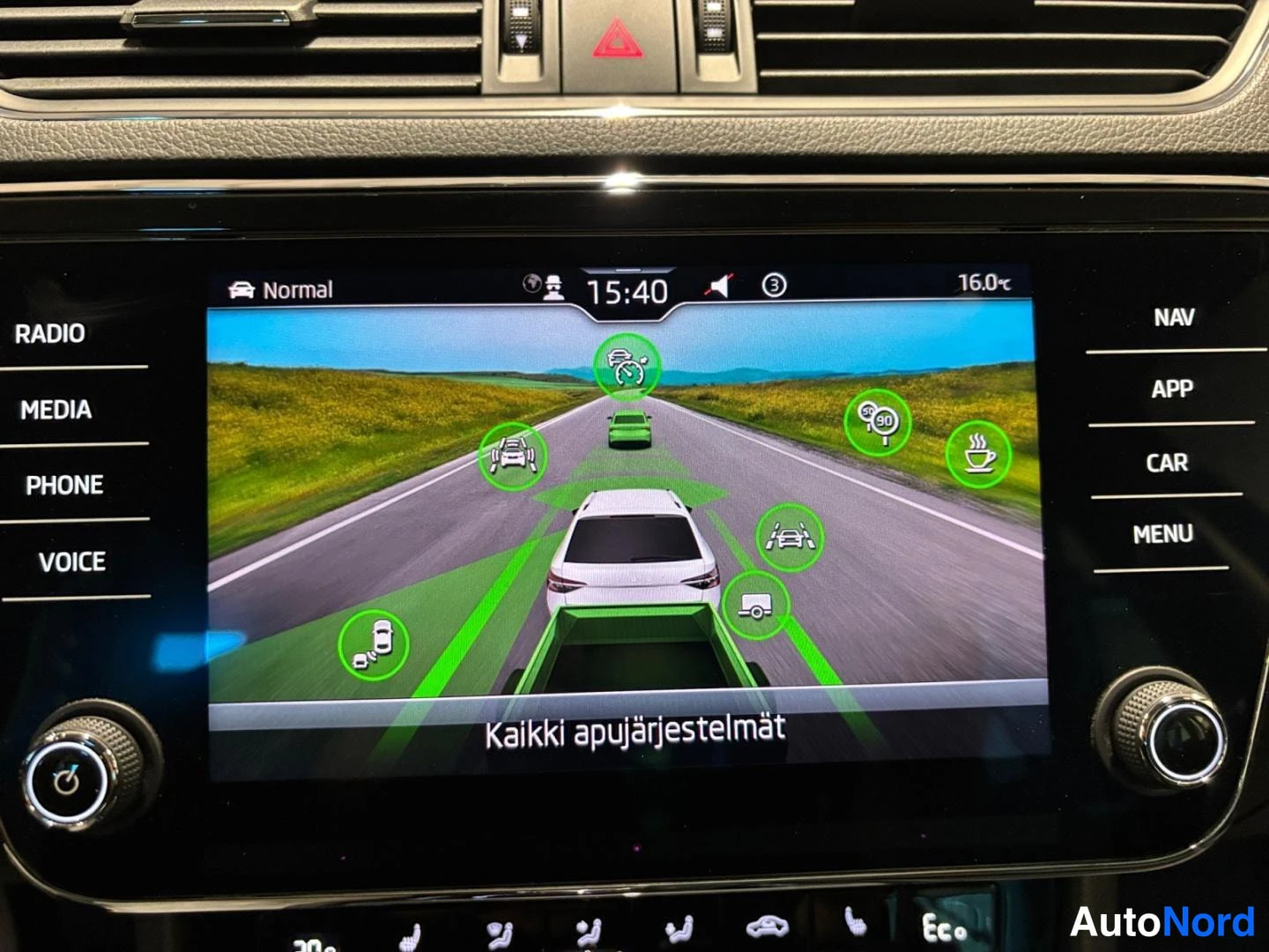 Muu: Kojelautaan upotettu infotainment-näyttö, jolla näkyy kuljettajaa avustavien järjestelmien kuvakekatsaus ja teksti 'Kaikki apujärjestelmät'. Näytön reunoilla RA