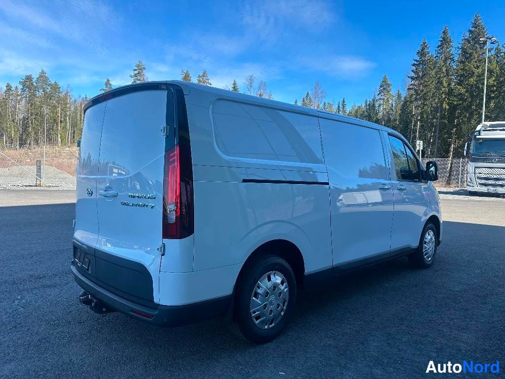 Takaviisto: Valkoinen Maxus Deliver 7 pakettiauto oikeanpuoleisesta takaoviuistokuvasta seisomassa puiden edessä.
