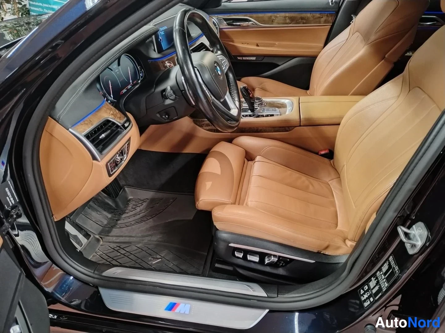 Muu: BMW:n etuistuintila ovelta katsottuna, ruskeat nahkaistuimet, puukoristeet kojelaudassa ja M-merkitty kynnyslista.