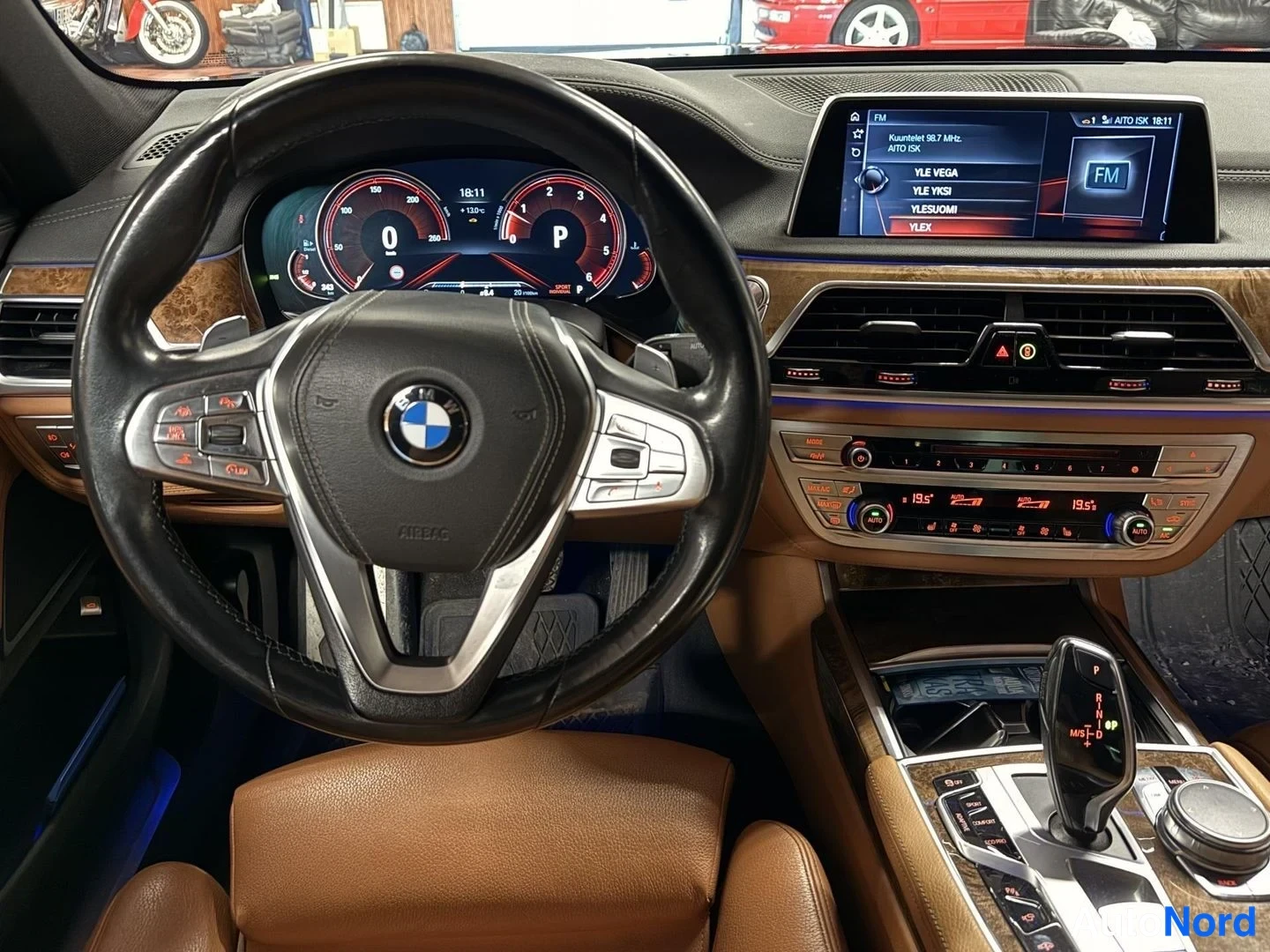 Muu: BMW:n kojelauta ja ohjauspyörä edestä kuvattuna, digitaaliset mittarit ja radiokanavavalikko näytöllä.