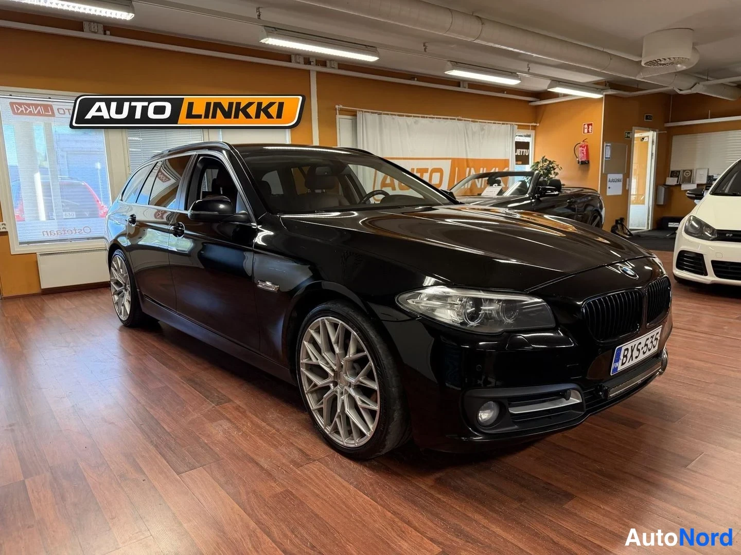 Etuviisto, nokka oikealle: Musta BMW-station wagon nähty etuviistosta oikealta auton sisätiloissa; etupaneeli, kylki ja hopeiset vanteet näkyvät, rekisterikilpi BX-535.
