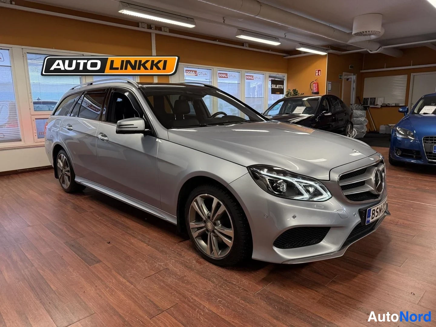 Etuviisto, nokka oikealle: Hopeanvärinen Mercedes-Benz farmari etu kolmannesvasen kulma sisätiloissa.
