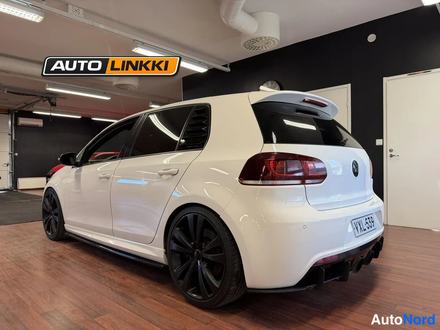 Takaviisto: Valkoinen Volkswagen Golf takakulmasta, tummat takavalot, mustat vanteet ja neljä pakoputkea, rekisteri.