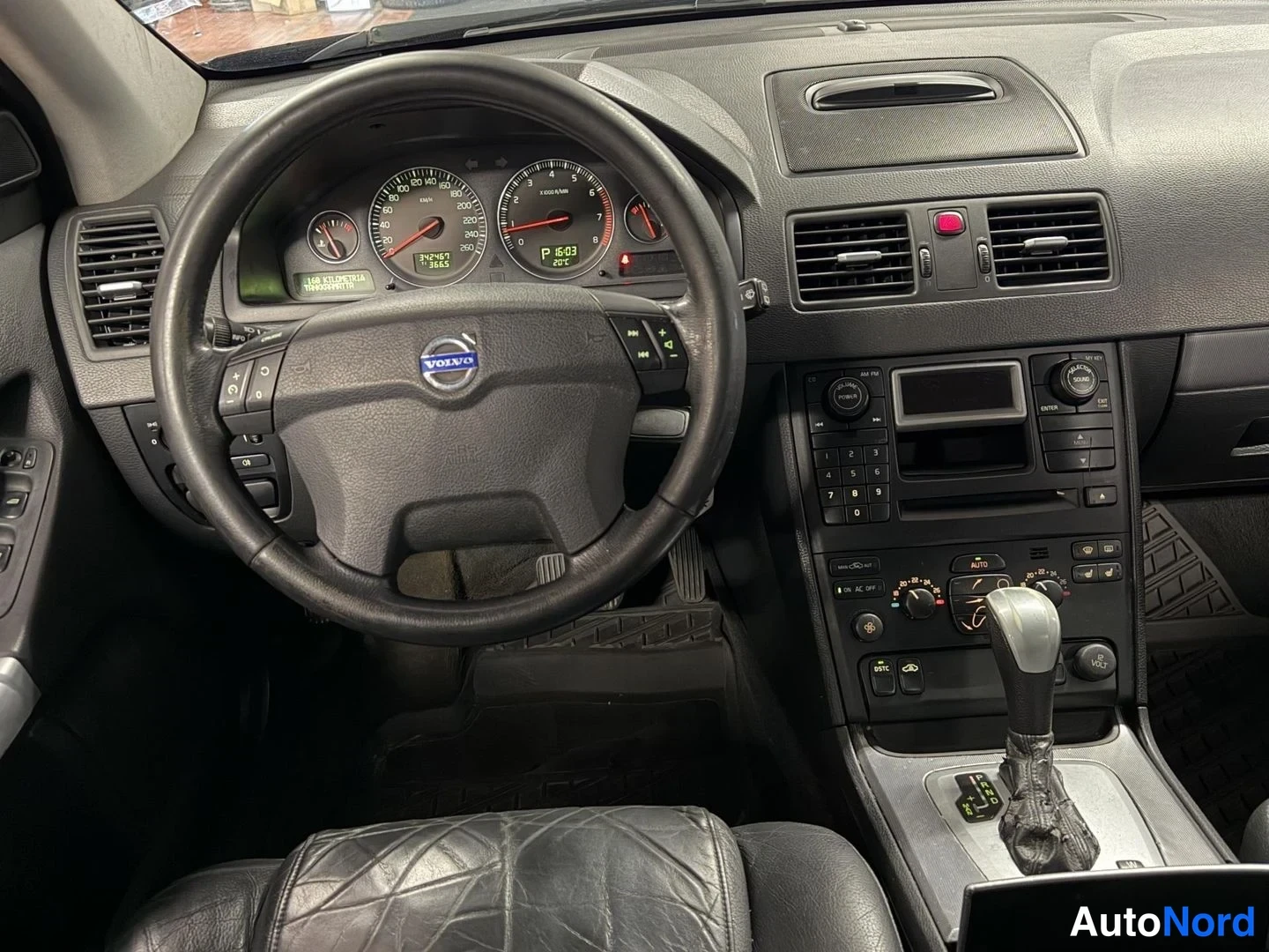 Muu: Ohjaamon näkymä: Volvo-ohjauspyörä, analogiset mittarit (nopeusmittari ja kierroslukumittari), radio ja automaattivaihteen valitsin.