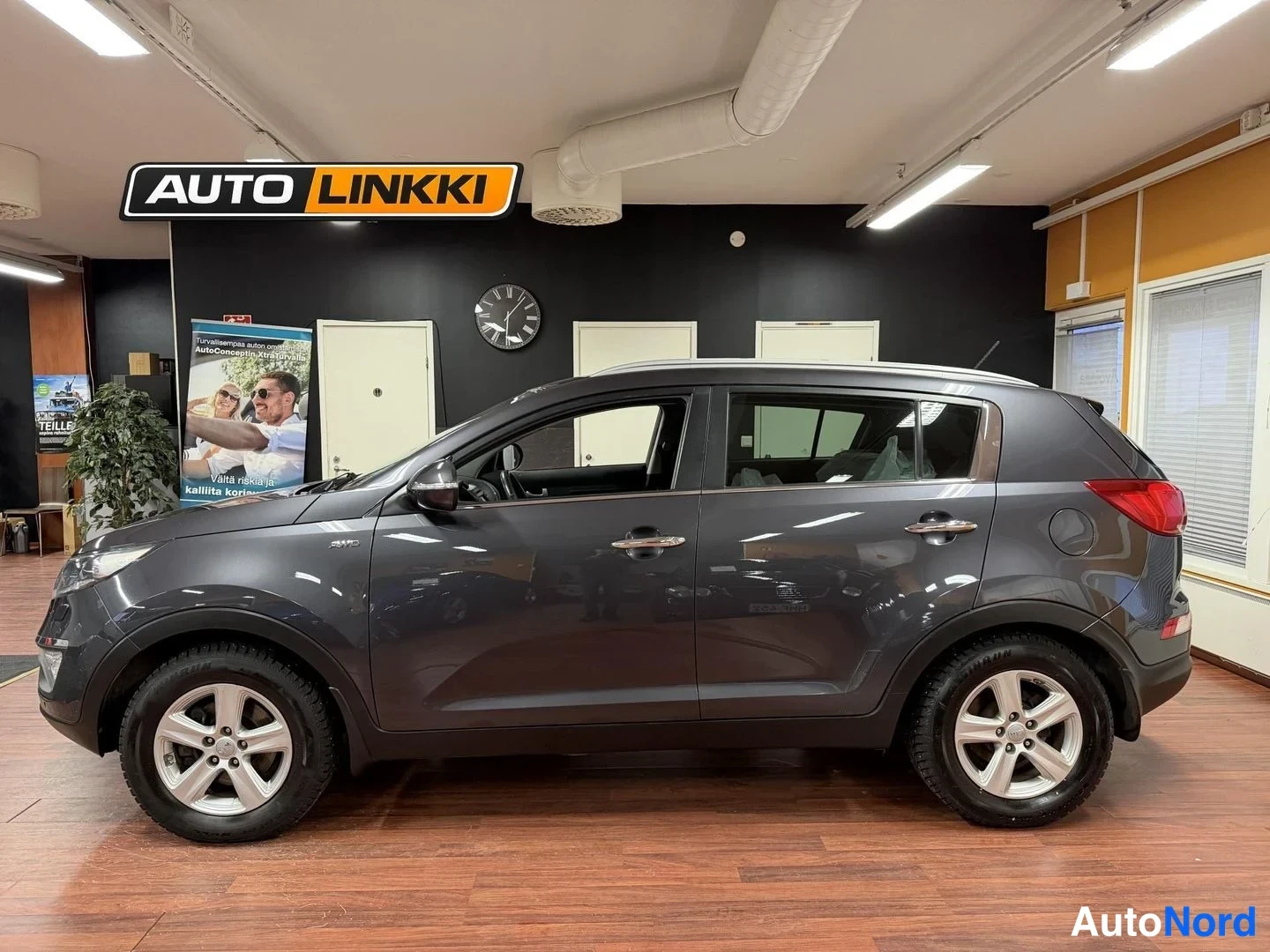Sivulta: Auton sivunäkymä vasemmalta, tummanharmaa Kia Sportage sisätiloissa.