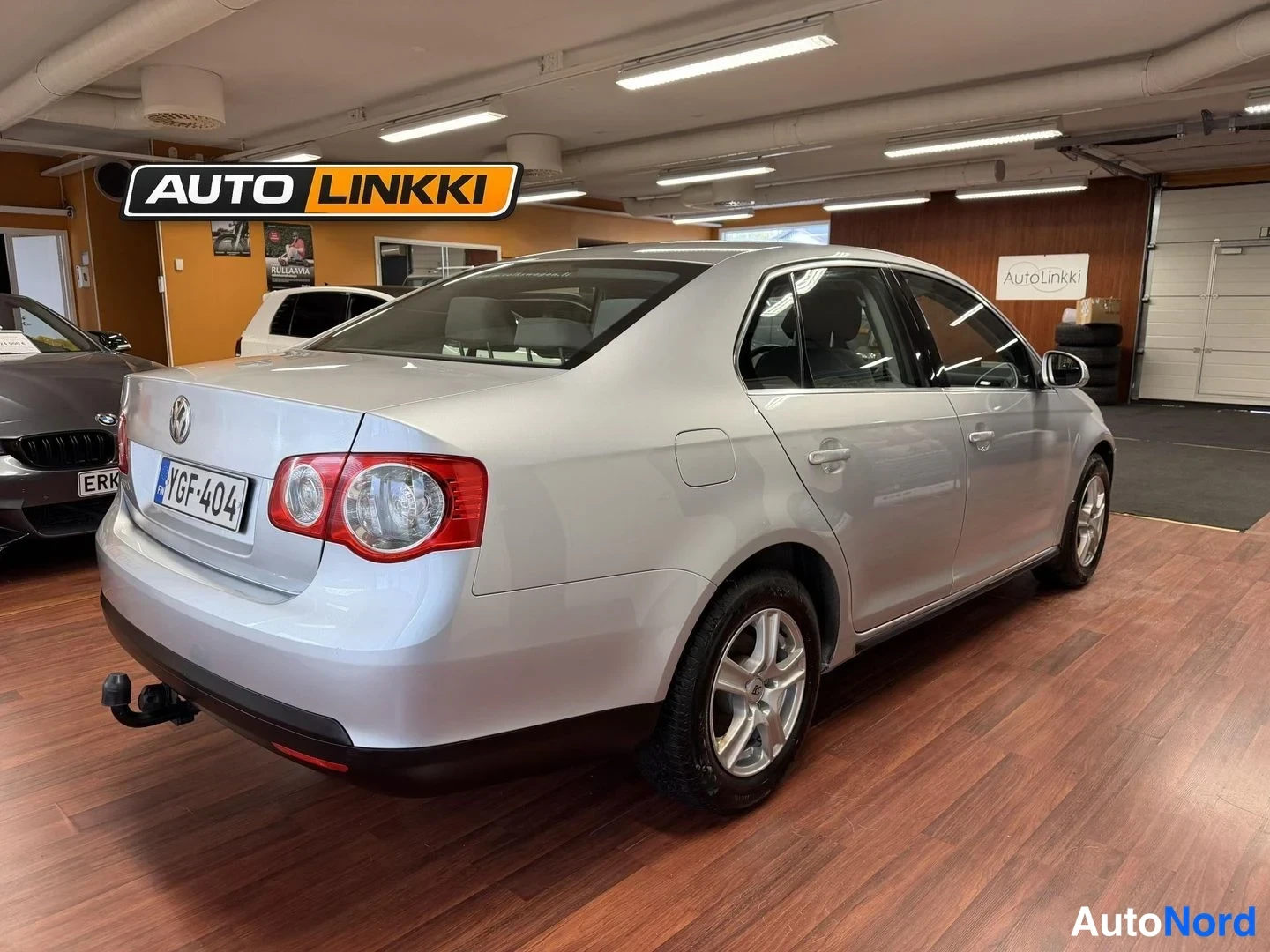 Takaviisto: Hopeanharmaa Volkswagen Jetta -sedan takakulmasta, perä vasemmalla, savuhella näkyy takapuskurissa.