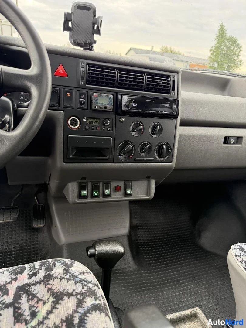 Muu: Kojelaudan keskiosan lähikuva: Pioneer-radio, mittareita ja kytkimiä, vaihdevipu ja lattiakytkimet.