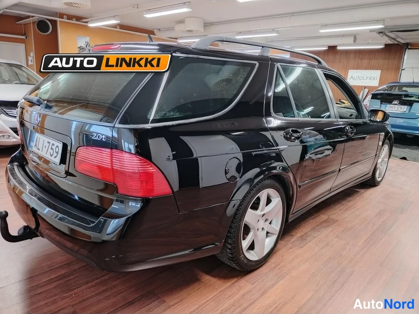 Takaviisto: Mustan Saab 9-5 -farmarin takakulmatäkki, rekisteritunnus, 2.0t-merkintä ja perävaunun koukku näkyvät.