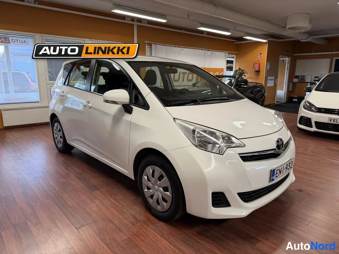 Etuviisto, nokka oikealle: Valkoinen Toyota Verso-S etuosa ja vasen kylki näkyvissä sisätiloissa.