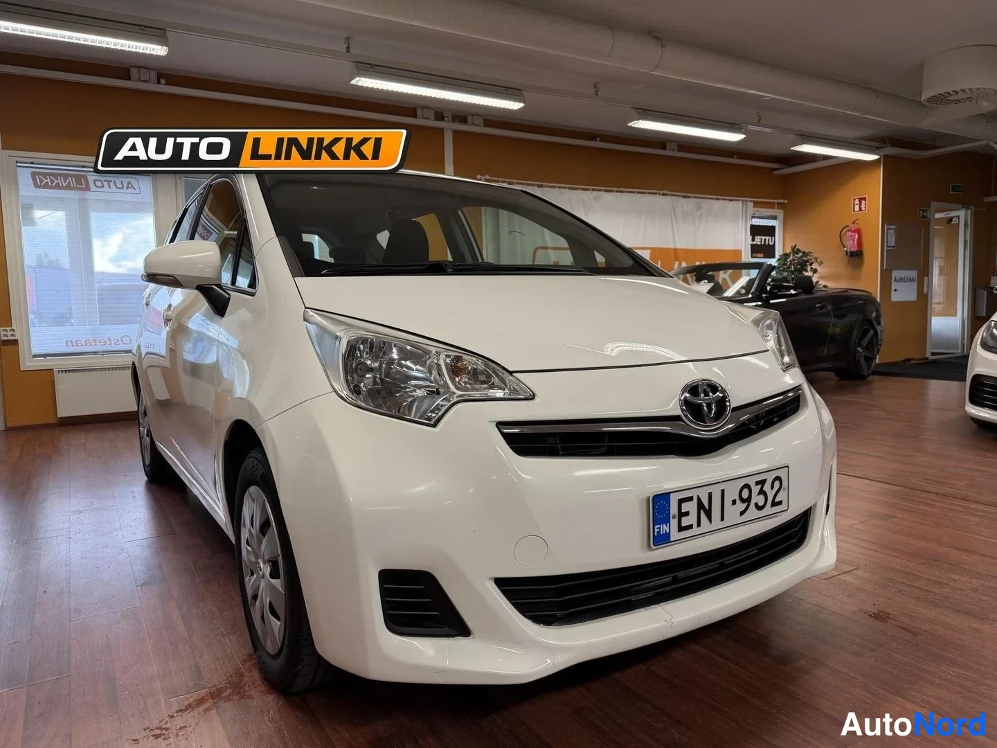 Etuviisto, nokka oikealle: Valkoinen Toyota Verso-S etukuva sisätiloissa, rekisteritunnus.