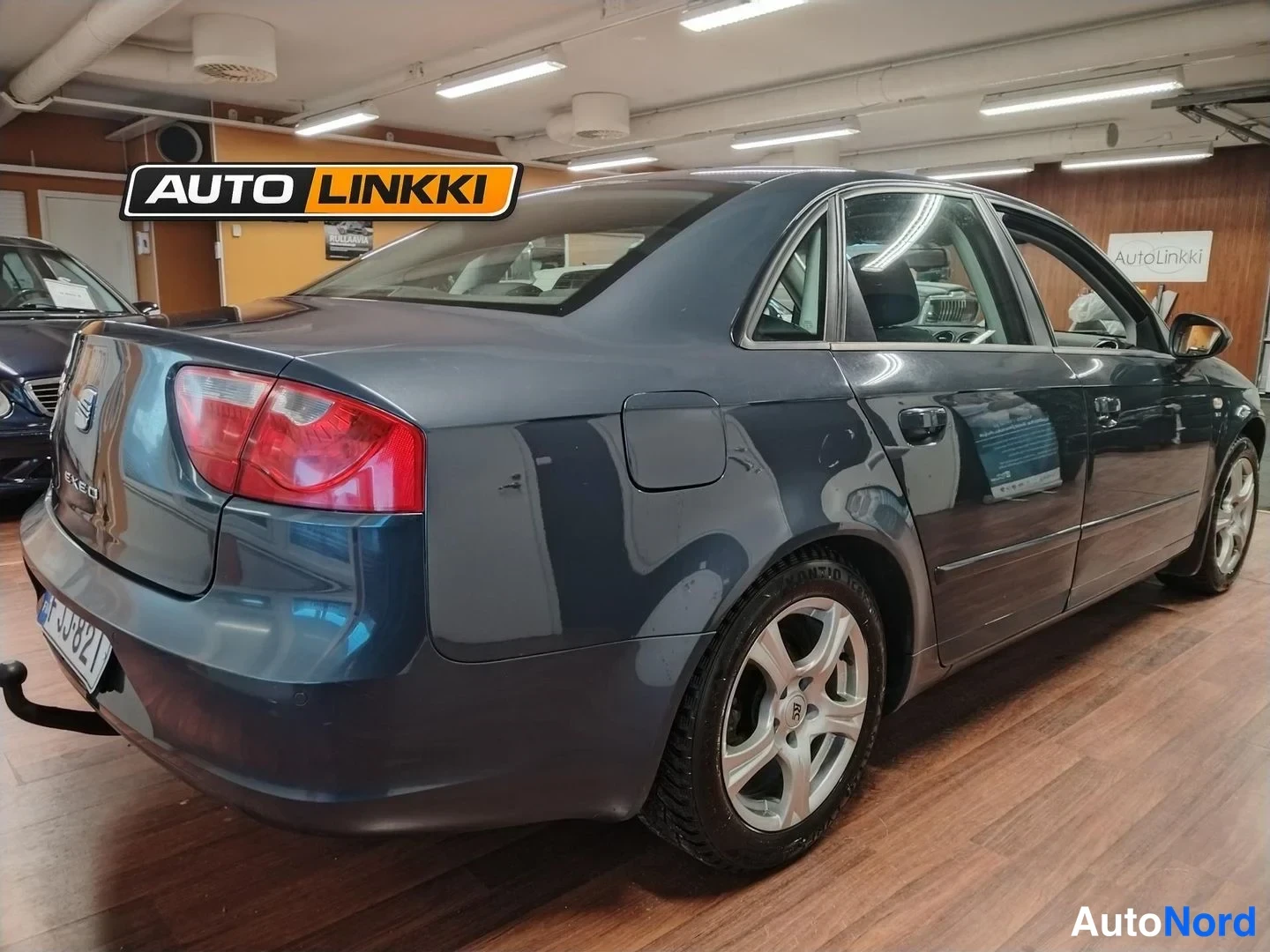 Takaviisto: Tummanharmaa Seat Exeo -sedan takakulmassa,(EXEO)-teksti takakannessa ja vetokoukku näkyvissä.