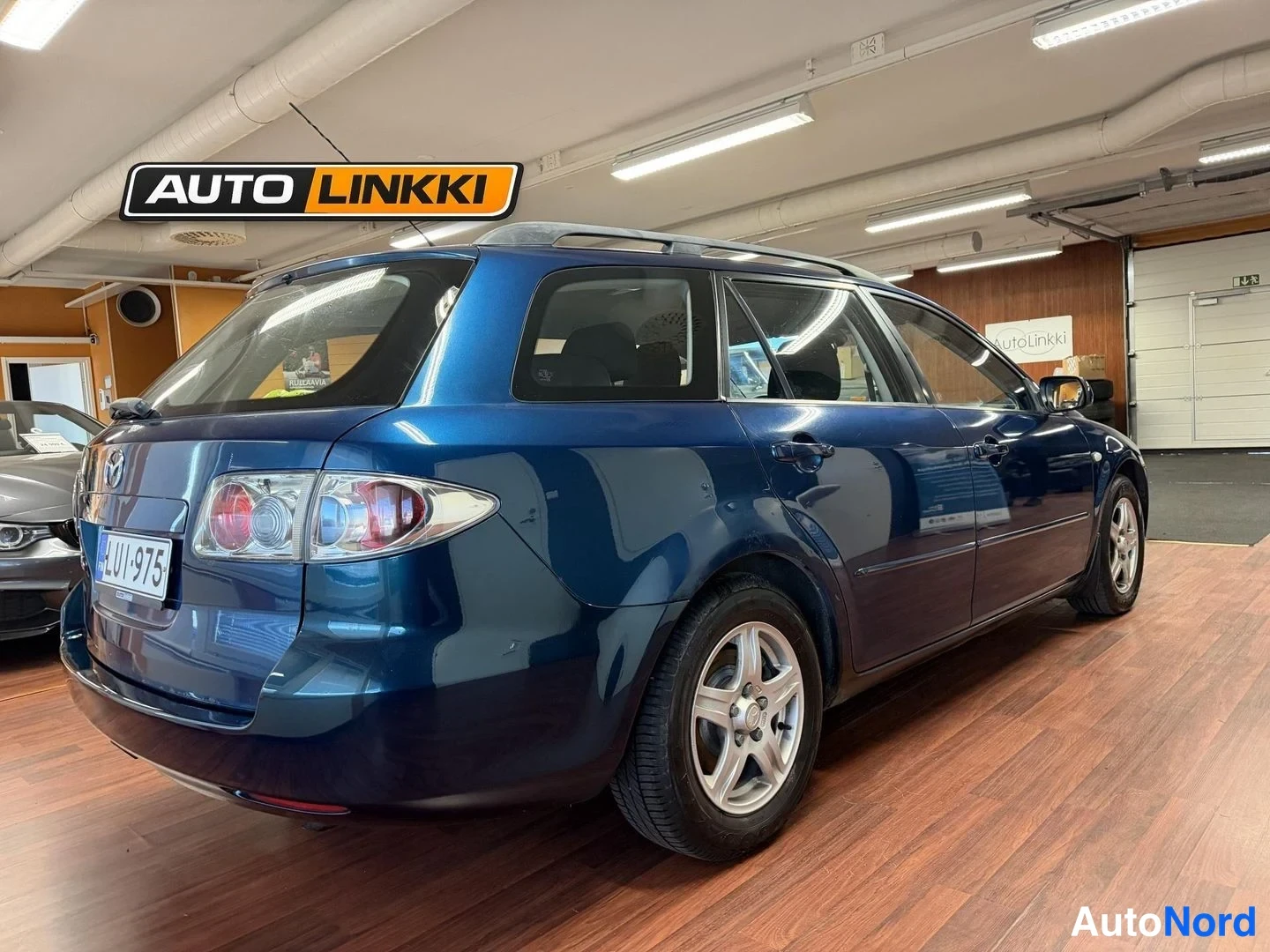 Takaviisto: Sininen Mazda 6 -farmari takaapäin kulmasta kuvattuna, rekisterikilpi näkyy perällä.