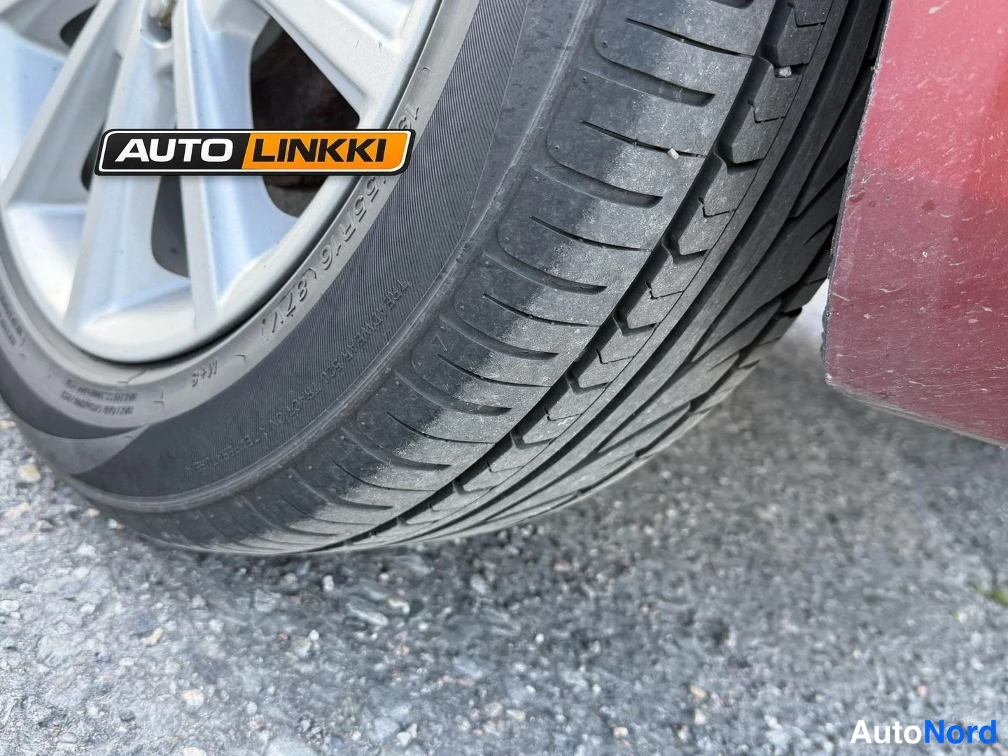 Muu: Lähikuva tummasta renkaasta ja hopeavanteesta; kyljessä lukee 195/55 R 16 87 H ja WRV-merkintä.