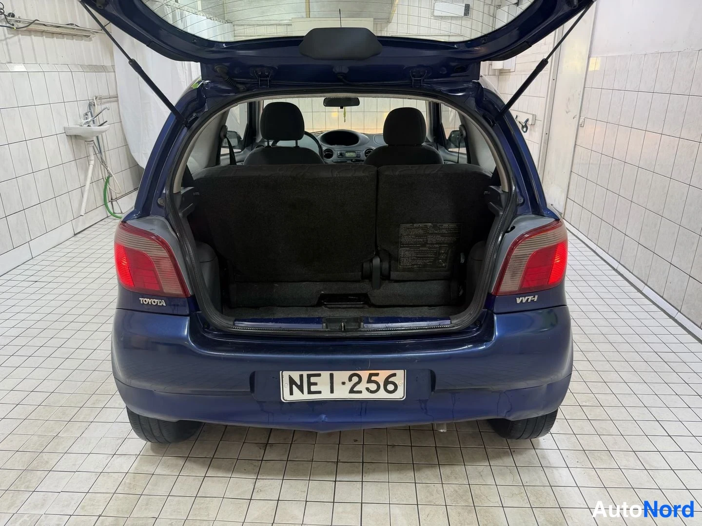 Takaa: Toyota Yarisin tavaratila avattuna, taitettujen selkänojien takaa näkyy matkalaukkuhylly; rekisterikilpi.