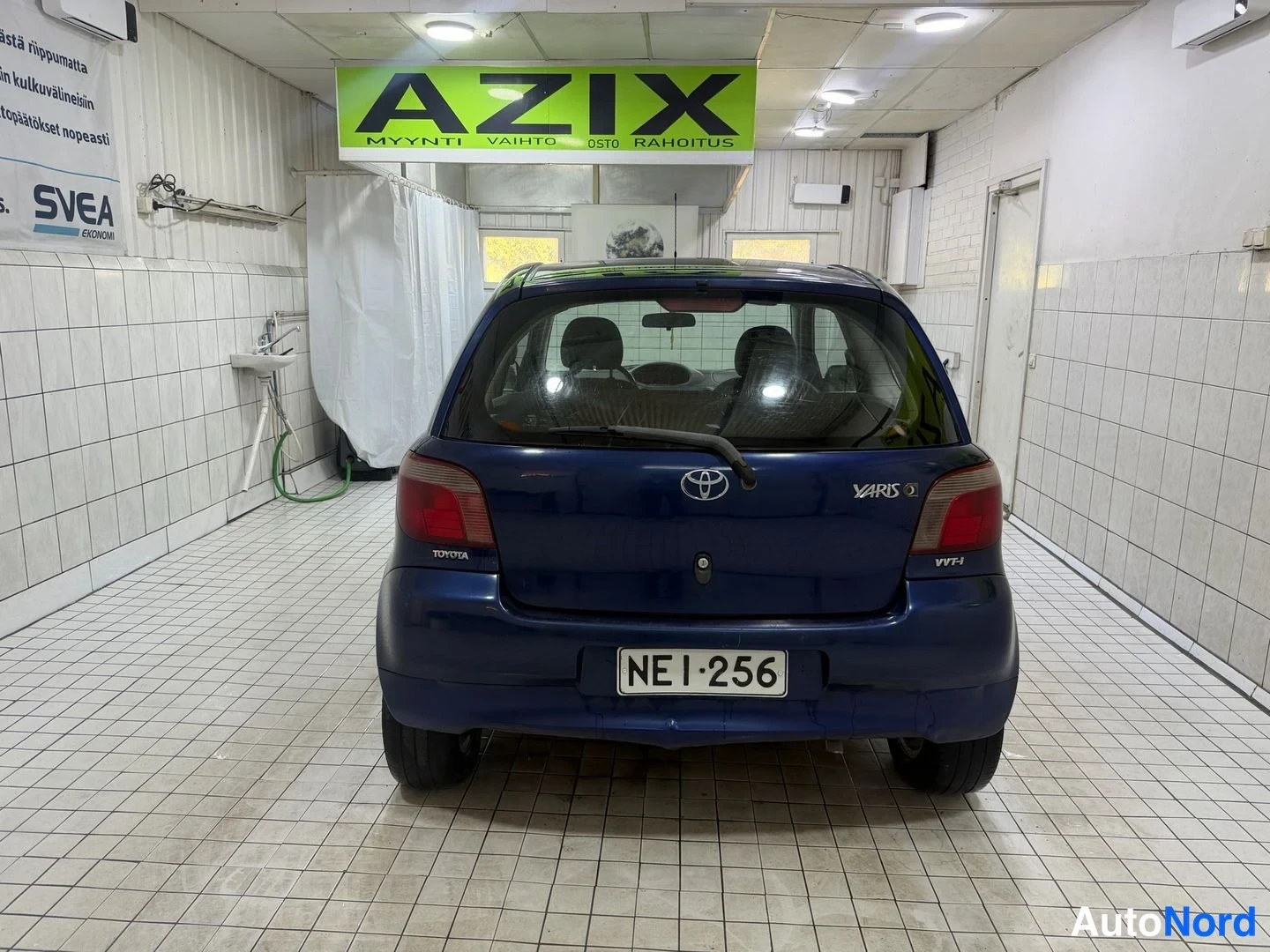Takaa: Tummansininen Toyota Yaris suoraan takaa kuvattuna, takaluukussa YARIS 1.3 VVT-i -merkinnät ja rekisteritunnus